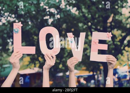 Hands holding up letters building word love on natural background Stock Photo