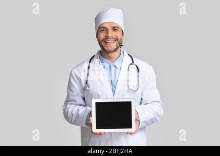 Cheerful doctor holding blank digital tablet in hands Stock Photo