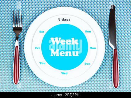 Plate with text "Week Menu", fork and knife on tablecloth background Stock Photo