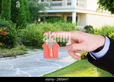 Key in hand on house background, Real estate concept Stock Photo