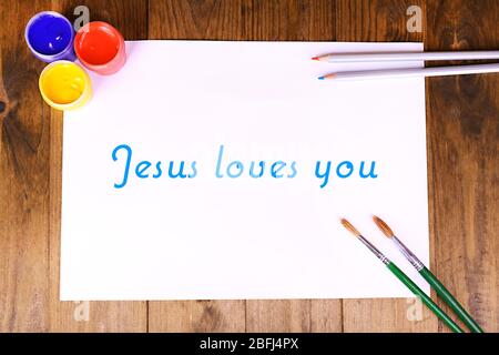 Jesus loves you text on paper on wooden table background Stock Photo