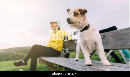 Asian woman making uphill with mountain bike. A woman looking around at lookout point with a dog at Oamaru, New Zealand. Stock Photo