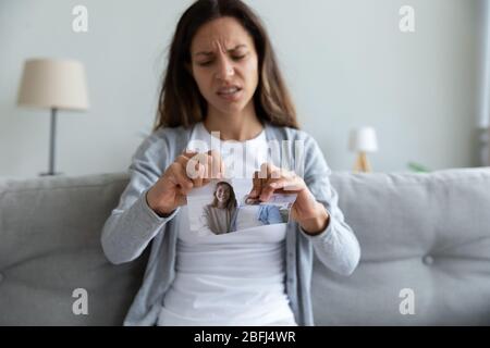 Depressed woman suffering from break up, tearing picture with husband Stock Photo
