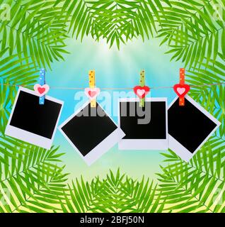 Photo cards hanging on clothesline on palm leaves background Stock Photo