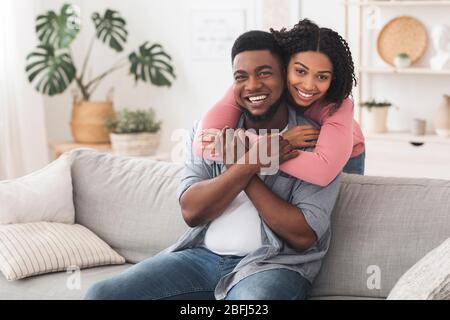 Happy Married Black Couple Cuddling At Home And Posing To Camera Stock Photo