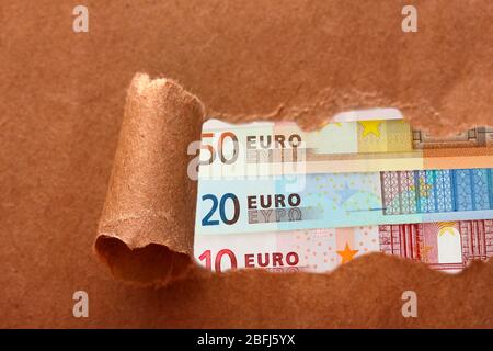 Euro banknotes through torn craft paper Stock Photo