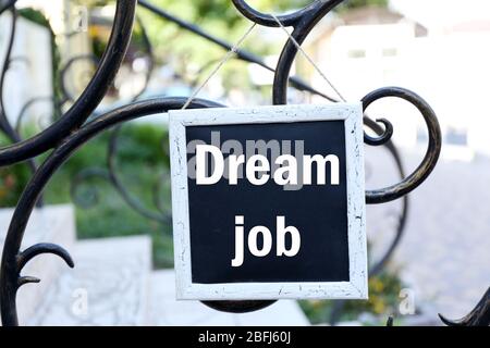 Signboard with Dream Job text on it hanging on metal fence Stock Photo