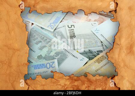 Euro banknotes through torn craft paper Stock Photo