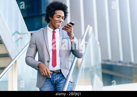 Black Businessman using a smartphone near an office building Stock Photo
