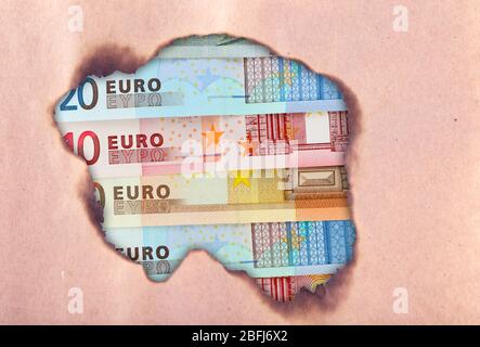 Euro banknotes through torn craft paper Stock Photo