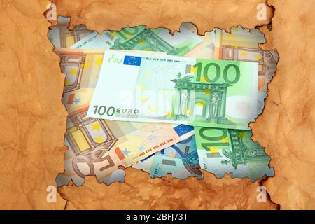 Euro banknotes through torn craft paper Stock Photo