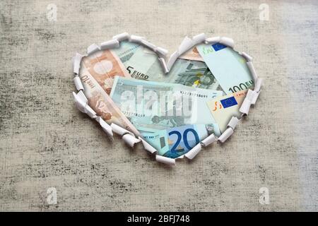 Euro banknotes through torn gray paper Stock Photo