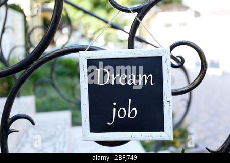 Signboard with Dream Job text on it hanging on metal fence Stock Photo