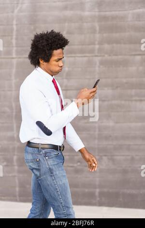 Concerned Black Businessman using his smartphone outdoors Stock Photo