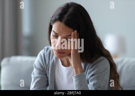 Unhappy thoughtful woman touching face, thinking about problems Stock Photo