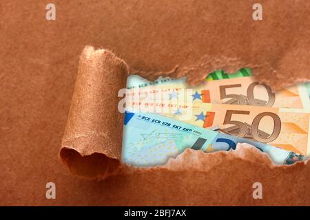 Euro banknotes through torn craft paper Stock Photo