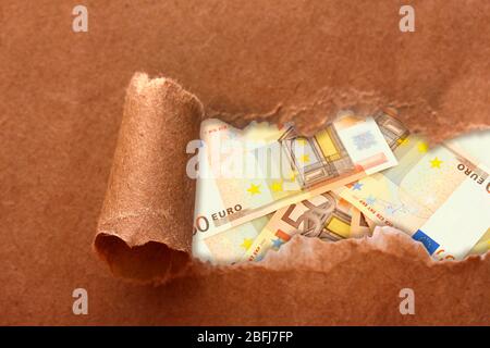 Euro banknotes through torn craft paper Stock Photo