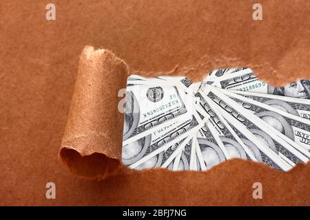 Dollars through torn craft paper Stock Photo