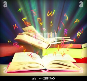 Many books with flying letters on table on bright background Stock Photo