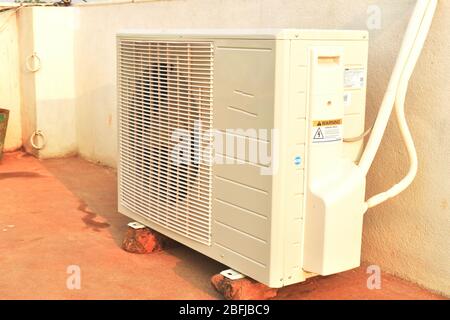 Air conditioner outdoor unit which is known as compressor is installed on the red bricks. in india Stock Photo