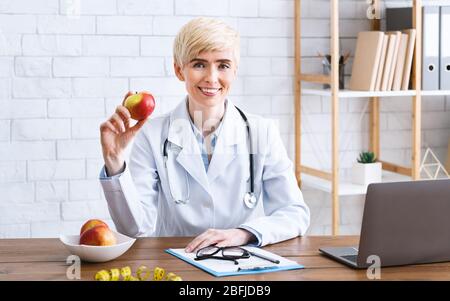 Nutritionist doctor in office at table with apple Stock Photo