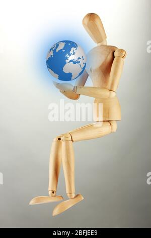 Wooden mannequin with Earth, on gray background Stock Photo