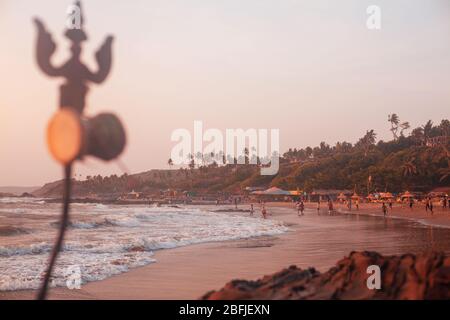 Trident totem near Shiva Face Rock Carving on Vagator Beach, Goa, India. Beautiful sunset and shore background. Northernmost beach of Bardez Taluka in Stock Photo