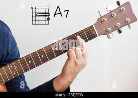 Learn Guitar - Man in a dark blue shirt playing guitar chords displayed on whiteboard, Chord A7 Stock Photo