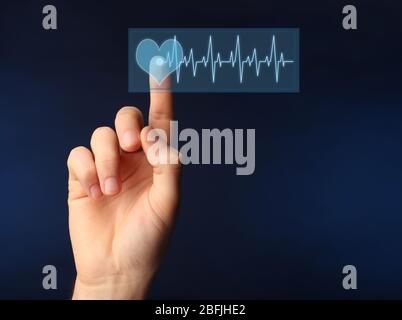 Hand pressing virtual button with heart diagram Stock Photo