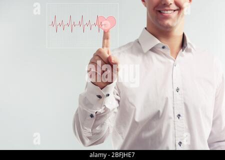 Young man pressing virtual button with heart diagram Stock Photo