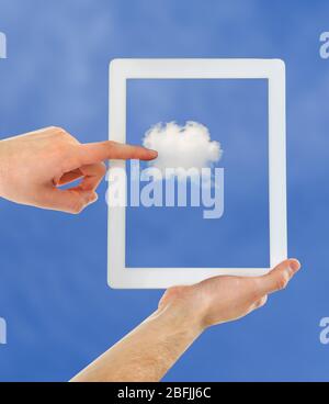 Hand touching cloud on tablet on sky background Stock Photo