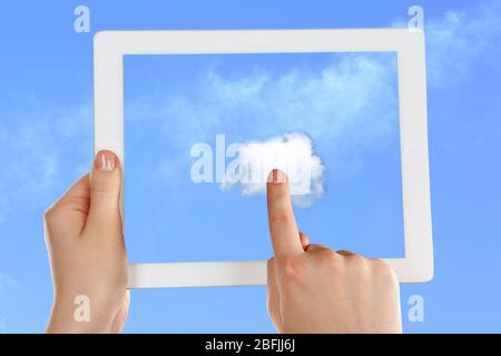 Hand touching cloud on tablet on sky background Stock Photo