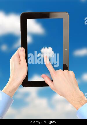 Hand touching cloud on tablet on sky background Stock Photo