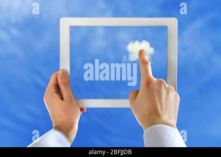 Hand touching cloud on tablet on sky background Stock Photo