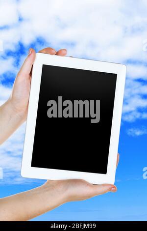 Hands holding tablet PC on sky background Stock Photo