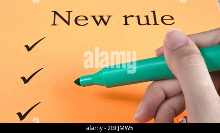 Hand writes marker on orange paper, text, message, new rules, art, study, creativity, design Stock Photo