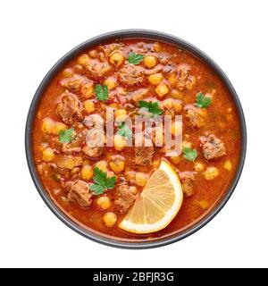 Moroccan Harira Soup in black bowl isolated on white bakcground. Harira is Moroccan Cuisine dish with lamb or beef meat, chickpeas, lentils, tomatoes Stock Photo