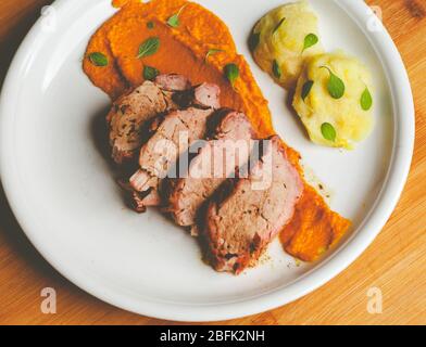 Pork fillet in a plate with carrot cream and fresh fruit Stock Photo