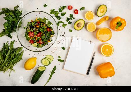 Juicy vegetarian salad at home for a quick bite. Top view. A book for writing recipes lies on the table. Copy space for text Stock Photo