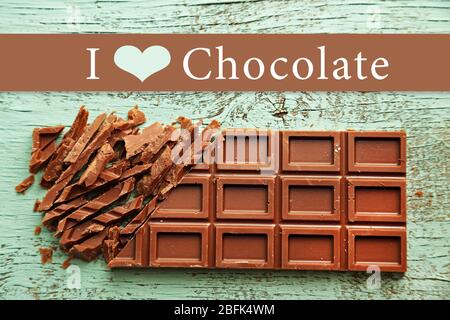 Chopped bar of chocolate on color wooden surface and space for text Stock Photo