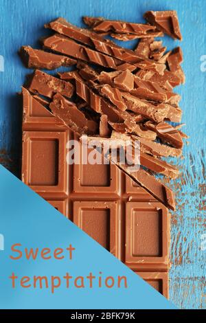 Chopped bar of chocolate on color wooden surface and space for text Stock Photo