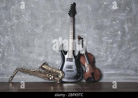 Electric guitar, saxophone and violin on gray wall background Stock Photo