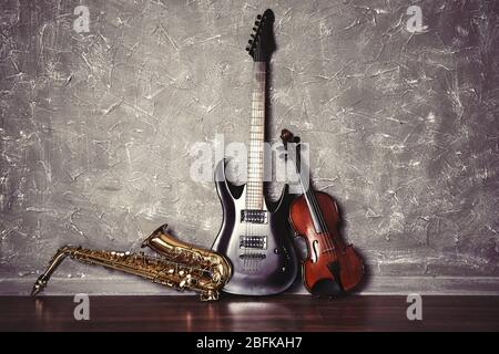 Electric guitar, saxophone and violin on gray wall background Stock Photo