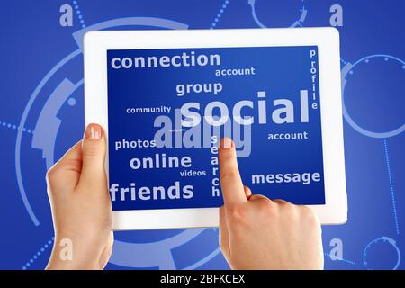 Social network and connected words on touch screen tablet-pc with finger touching screen, close up Stock Photo