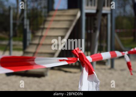 A red and white plastic barrier extends in front of a children's playground that is in the background Stock Photo