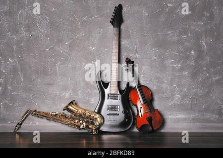 Electric guitar, saxophone and violin on gray wall background Stock Photo