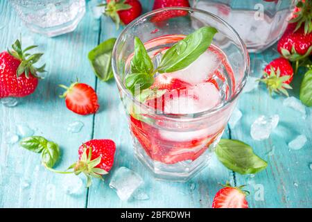Strawberry and basil detox infused water. Summer diet healthy drink with strawberries and basil leaves. Wooden background copy space Stock Photo