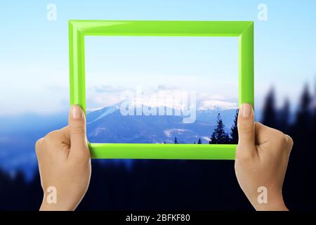 Woman hands holding empty frame on nature background Stock Photo