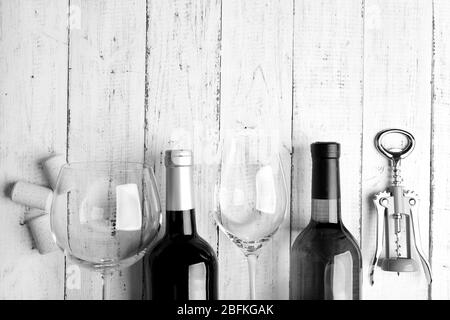 Bottles of wine, glass and corkscrew on wooden table,  black and white retro stylization Stock Photo