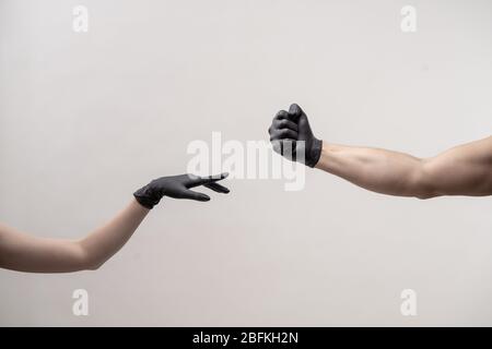 Hands in black silicone gloves stretches to each other to touch Stock Photo